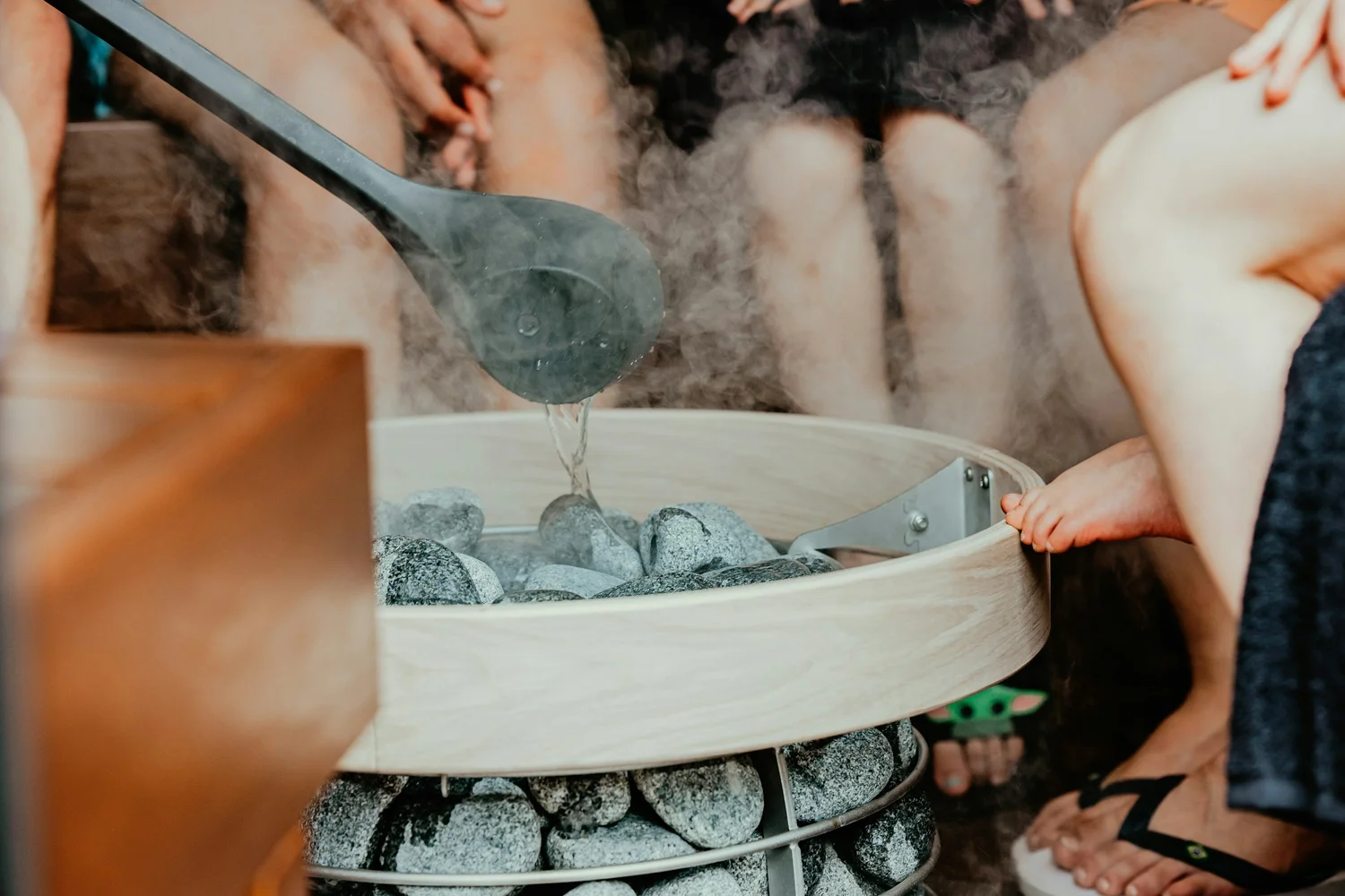 Water being poured over hot sauna stones inside The Cedar Room